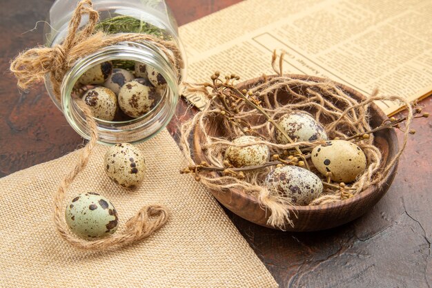 Zijaanzicht van boerderij verse eieren in een gevallen glas en houten pot op een bruine achtergrond