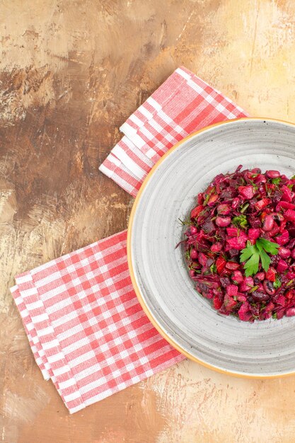 Gratis foto zijaanzicht van bord van een rode salade aan de rechterkant met greens erop met geruit servet aan de zijkant op een houten backgorund