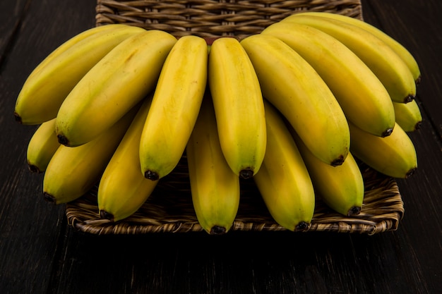 Gratis foto zijaanzicht van bos van bananen in een rieten mand op dark