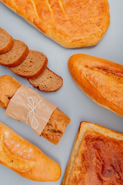 Zijaanzicht van brood als knapperig zwart-wit stokbrood met zelfgemaakte tandir-broden en gesneden roggebrood op blauw oppervlak