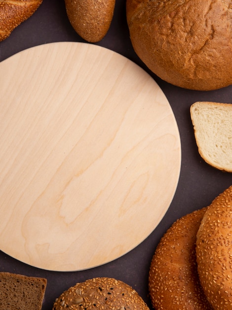 Zijaanzicht van brood als maïskolf bagel wit en roggebrood sneetjes met snijplank op kastanjebruine achtergrond