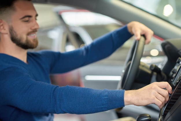 Zijaanzicht van brunette man met baard die in de auto zit