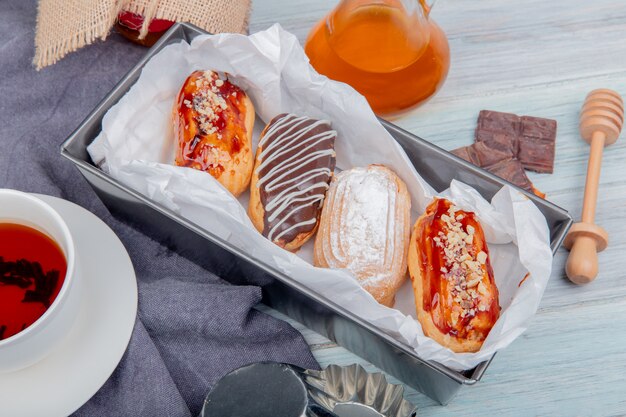 Zijaanzicht van cakes met boter chocoladekop thee rond op doek en houten oppervlakte