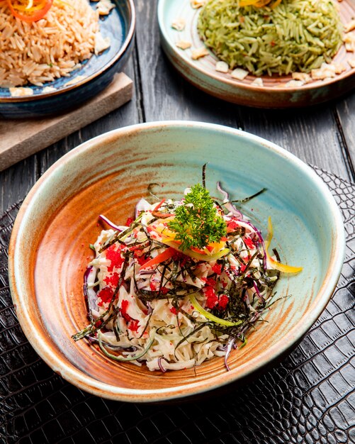 Zijaanzicht van Chinese salade met gehakte koolgroene paprika's en zeekool die met rode kaviaar op een plaat wordt verfraaid
