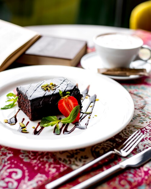 Zijaanzicht van chocoladecake dat met aardbei op een plaat wordt verfraaid