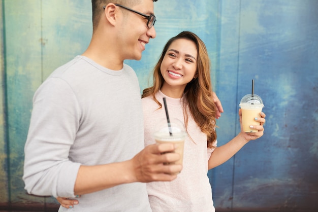 Zijaanzicht van daterend paar dat milkshakes op een promenade heeft lopen