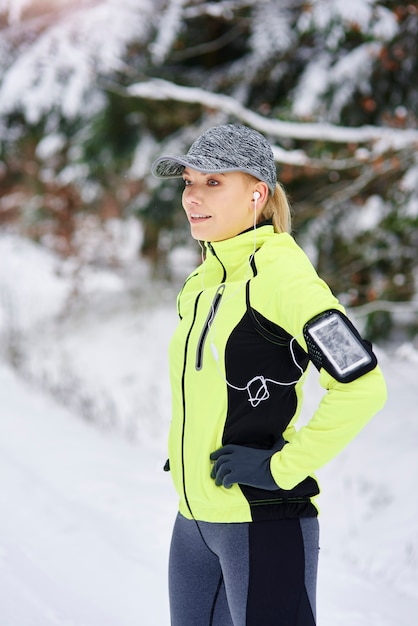 Zijaanzicht van de glimlachende vrouw die vóór het hardlopen opwarmt