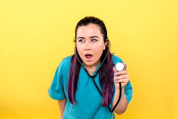 Zijaanzicht van de goede dokter met phonendoscope op de gele muur