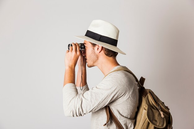 Zijaanzicht van de hipster man met behulp van een verrekijker