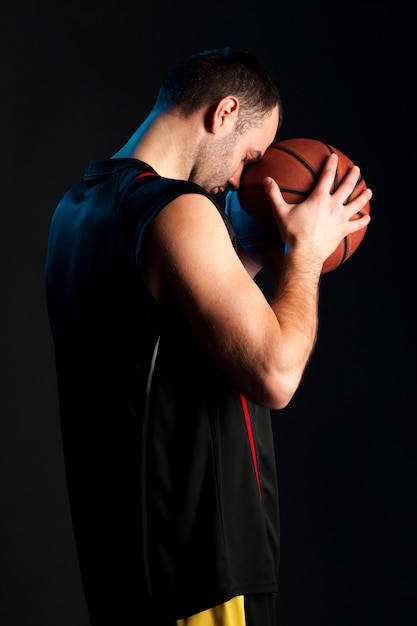 Zijaanzicht van de holdingsbal van de basketbalspeler aan zijn voorhoofd