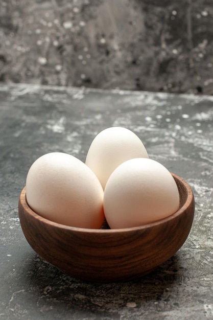 Zijaanzicht van de kom met eieren gecentreerd op een donkergrijze tafel op een donkere achtergrond