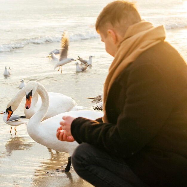 Zijaanzicht van de mens aan het strand in de winter met vogels