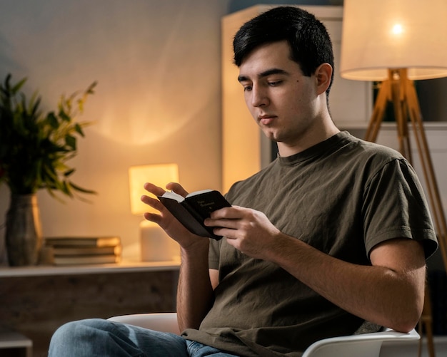 Zijaanzicht van de mens die de bijbel op de stoel leest