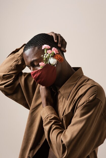 Zijaanzicht van de mens die gezichtsmasker en bloemen draagt