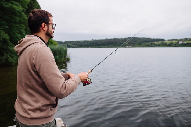 Zijaanzicht van de mens die in het idyllische meer vissen