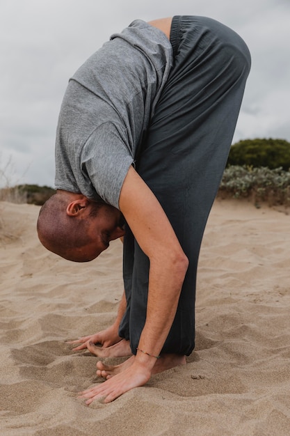 Zijaanzicht van de mens in yogapositie buitenshuis