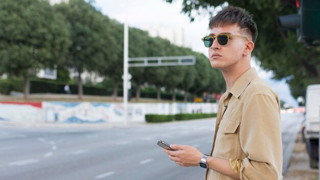 Zijaanzicht van de mens met zonnebril in de smartphone van de stadsholding