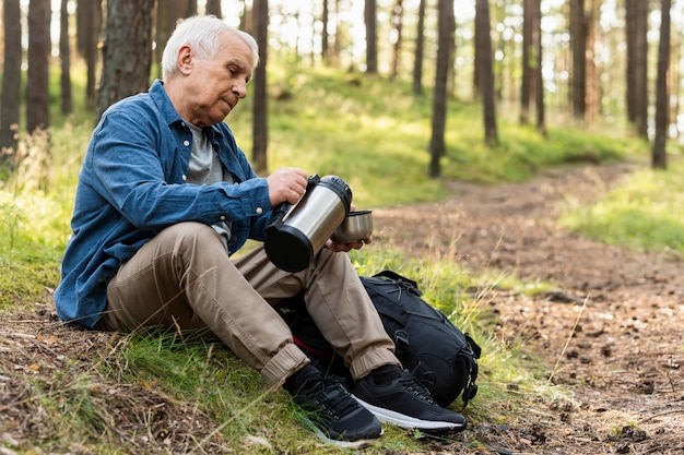 Gratis foto zijaanzicht van de oudere man in de natuur met rugzak