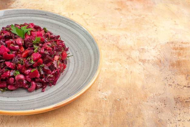 Zijaanzicht van de plaat van een rode salade aan de linkerkant met greens erop op een houten backgorund