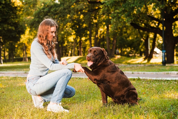 Zijaanzicht van de poot van een vrouw het schudden hond in tuin