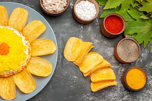 Zijaanzicht van de salade met kruidenchips en bladeren aan de rechterkant op een donkere achtergrond