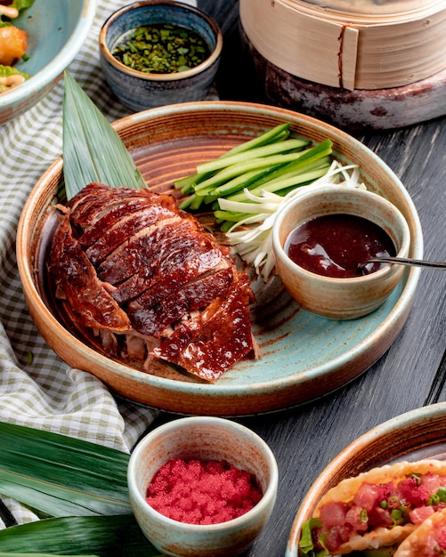 Zijaanzicht van de traditionele Aziatische eend van voedselpeking met komkommers en saus op een plaat