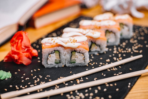 Zijaanzicht van de traditionele Japanse sushi van keuken Philadelphia sushi met zalm Philadelphia kaaskomkommer avocado op een zwarte raad