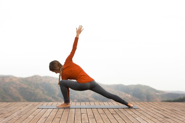 Zijaanzicht van de vrouw buiten in de natuur die yoga doet