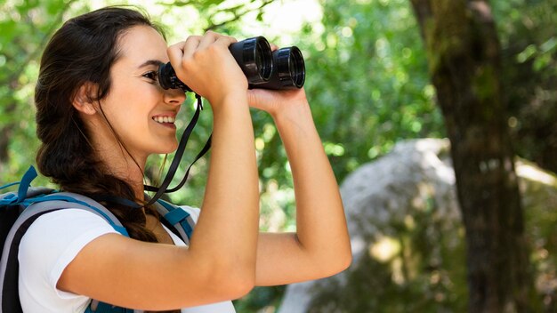 Zijaanzicht van de vrouw die de natuur bewondert door een verrekijker