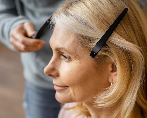 Zijaanzicht van de vrouw die haar kapsel thuis krijgt