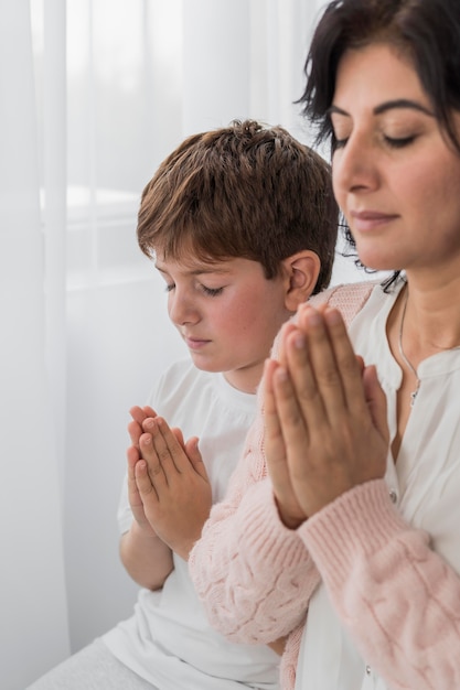 Zijaanzicht van de vrouw die met haar kind bidt