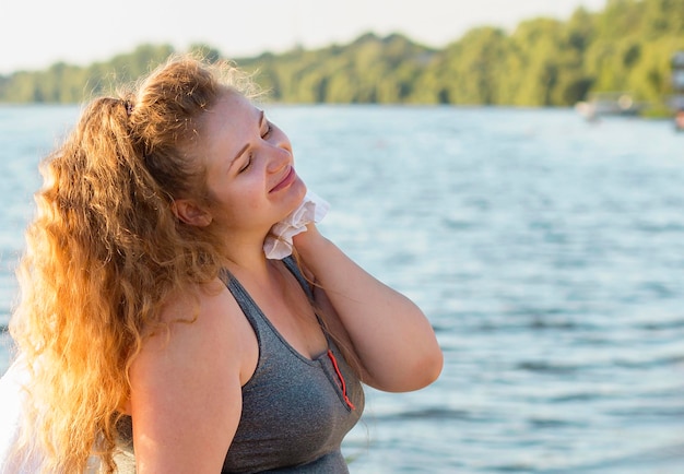Zijaanzicht van de vrouw die na het trainen aan het meer met exemplaarruimte rust