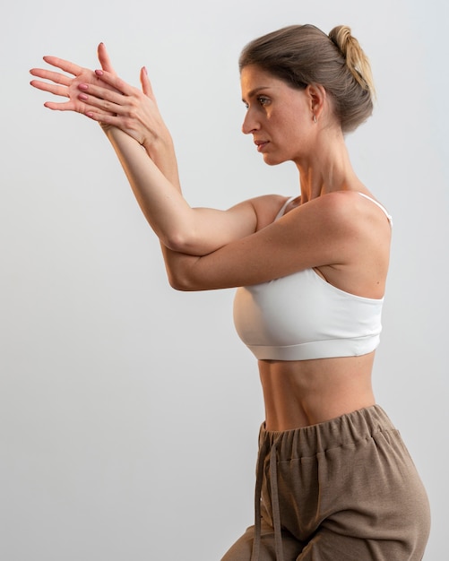 Gratis foto zijaanzicht van de vrouw die thuis yoga beoefent