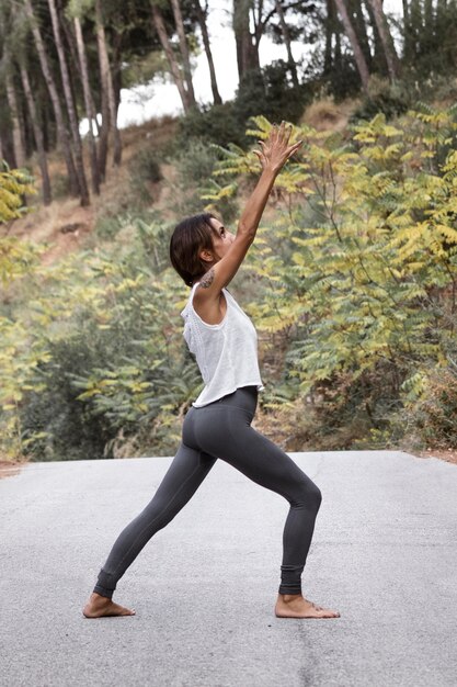 Zijaanzicht van de vrouw die yoga in de natuur doet