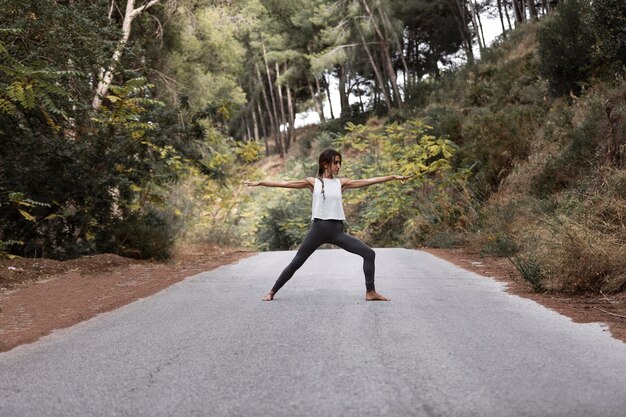 Zijaanzicht van de vrouw die yoga op de weg doet