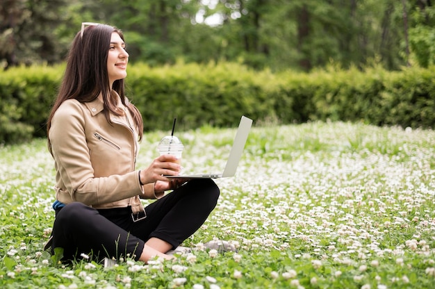 Zijaanzicht van de vrouw met laptop buiten in de natuur