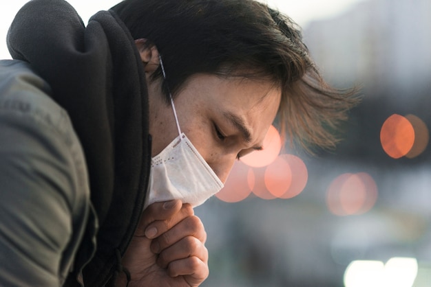 Gratis foto zijaanzicht van de zieke man met medische masker hoesten