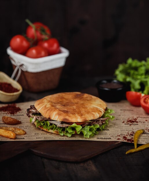 Zijaanzicht van doner kebab met gebakken aardappelen op een houten snijplank