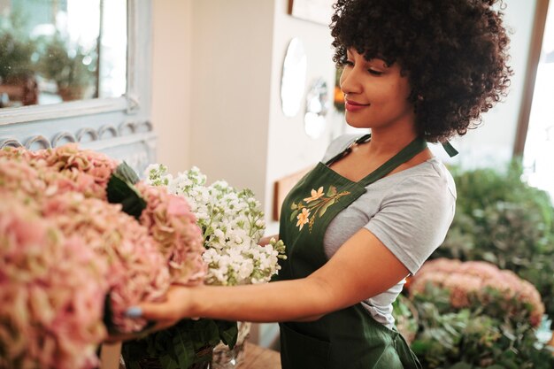 Zijaanzicht van een afro Afrikaanse vrouw die bloemboeket bekijkt