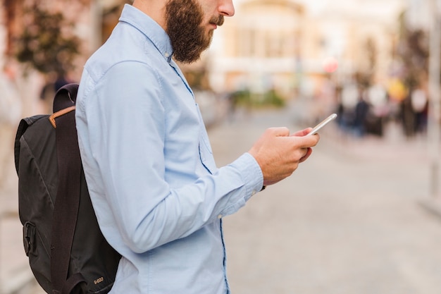 Gratis foto zijaanzicht van een bebaarde man met behulp van mobiele telefoon