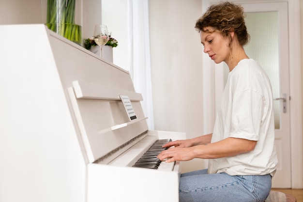 Zijaanzicht van een blonde vrouw die de piano speelt