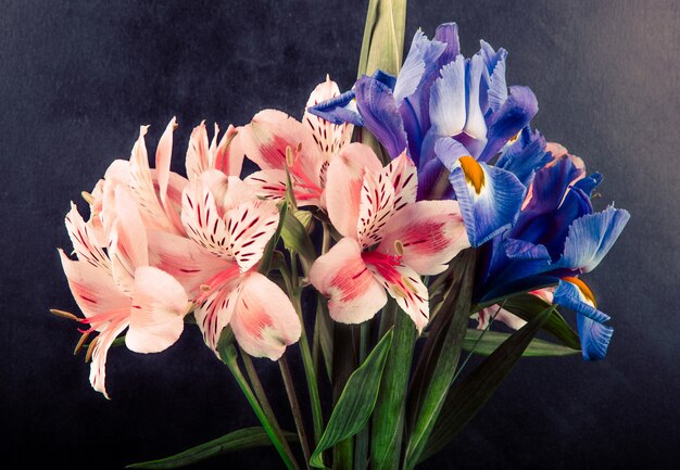 Zijaanzicht van een boeket van roze en paarse kleur alstroemeria en iris bloemen op zwarte achtergrond