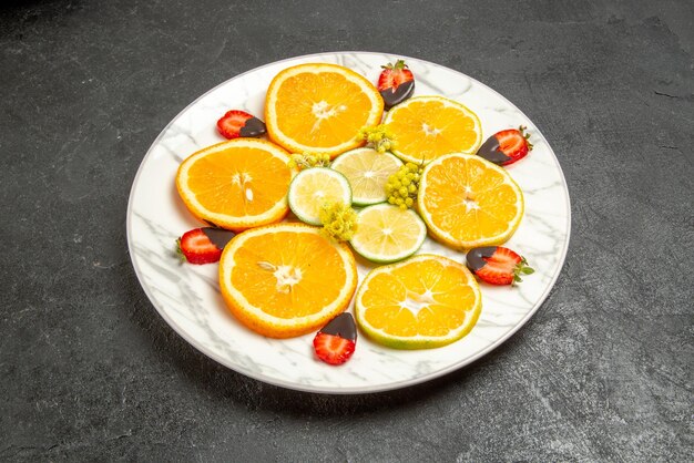 Zijaanzicht van een bord met fruitschaal met kleurrijke fruitchocolade in het midden van een grijze tafel