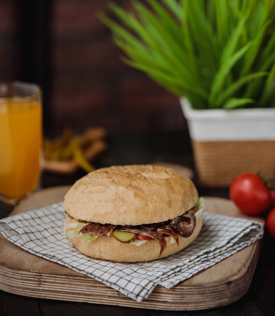 Zijaanzicht van een hamburger met vlees en sap in een glas op tafel