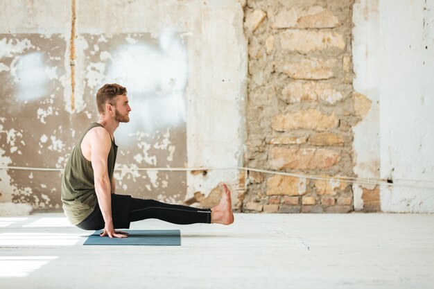 Zijaanzicht van een jonge man die yoga-oefeningen doet