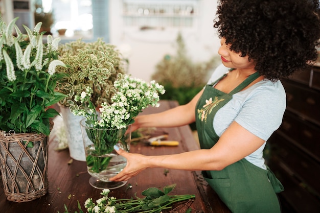 Zijaanzicht van een jonge vrouw die bos van witte bloemen in vaas schikken