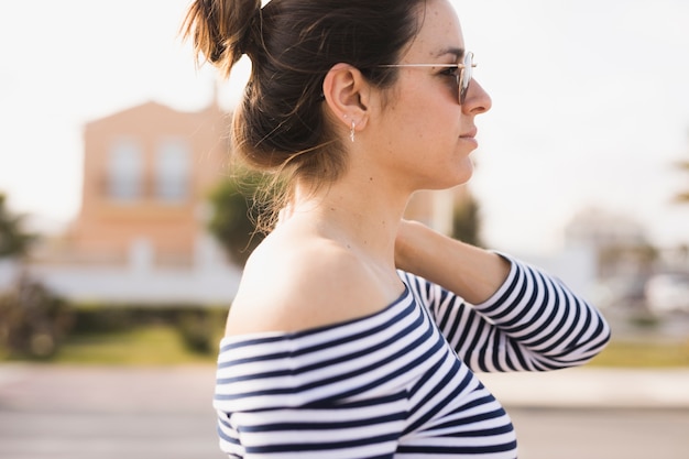 Gratis foto zijaanzicht van een jonge vrouw die zonnebril draagt die weg eruit zien