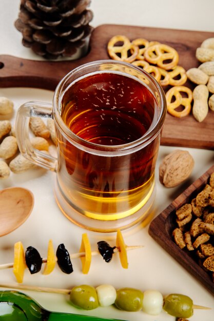 Zijaanzicht van een mok bier met verschillende zoute snacks op tafel