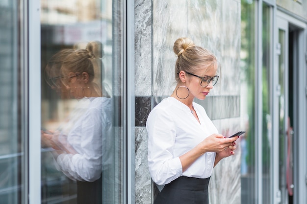 Zijaanzicht van een onderneemster die cellphone gebruikt