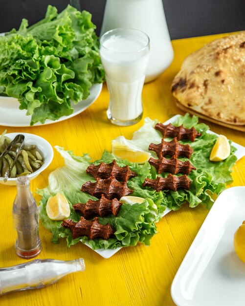 Zijaanzicht van een rauw vleesgerecht in Turkse keukens cig kofte met citroen op sla